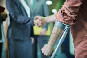 man on crutches shaking hands