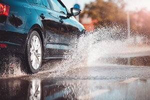 black car splashing water on road