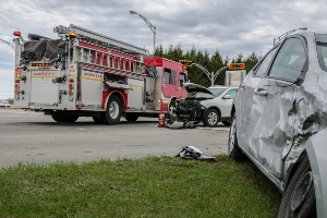 Paramedics and damaged vehicle at a car crash scene.