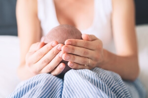 mother holding child on her lap; cradling the baby's head